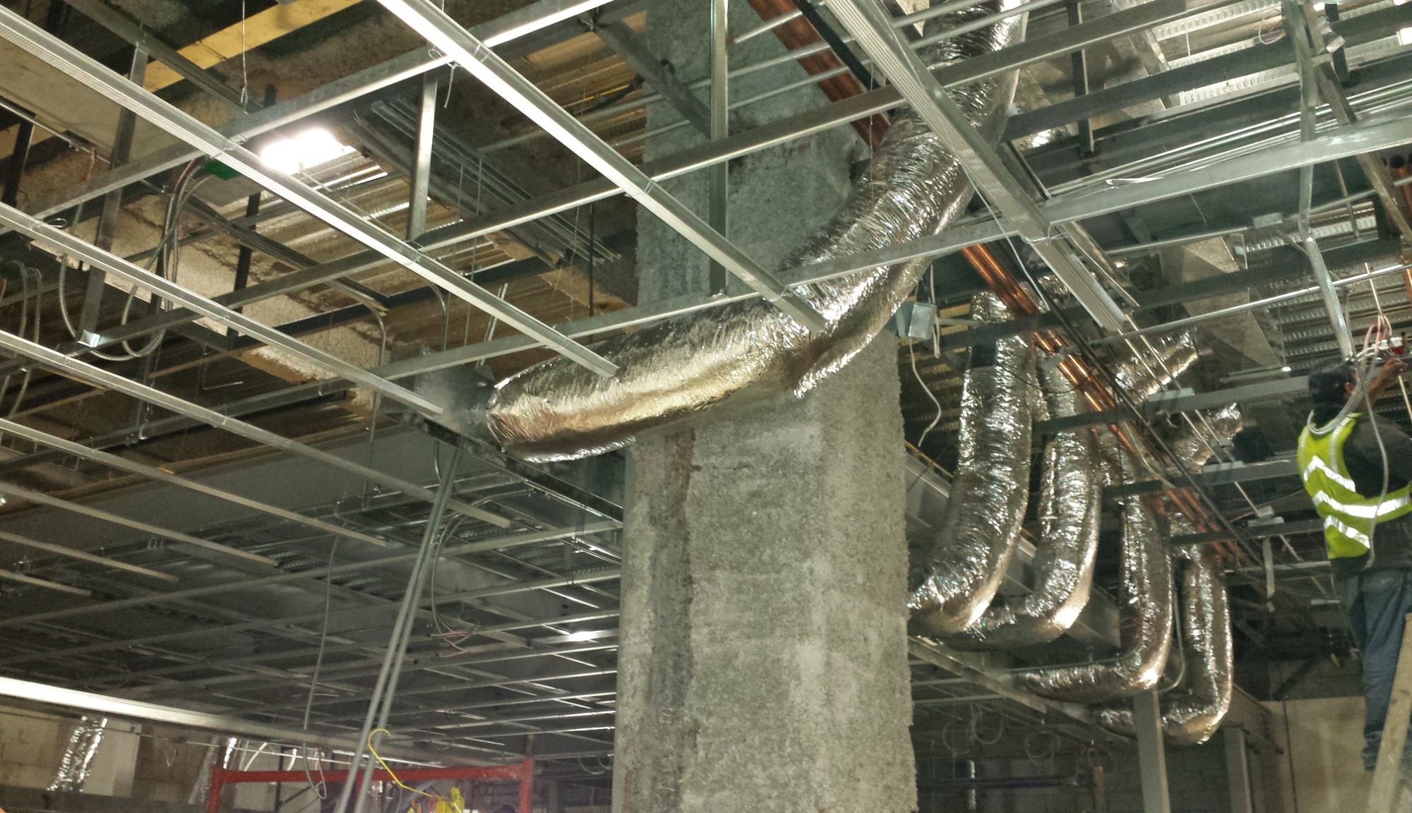 Instalaciones y ductos expuestos sobre la estructura de un plafón durante una obra.